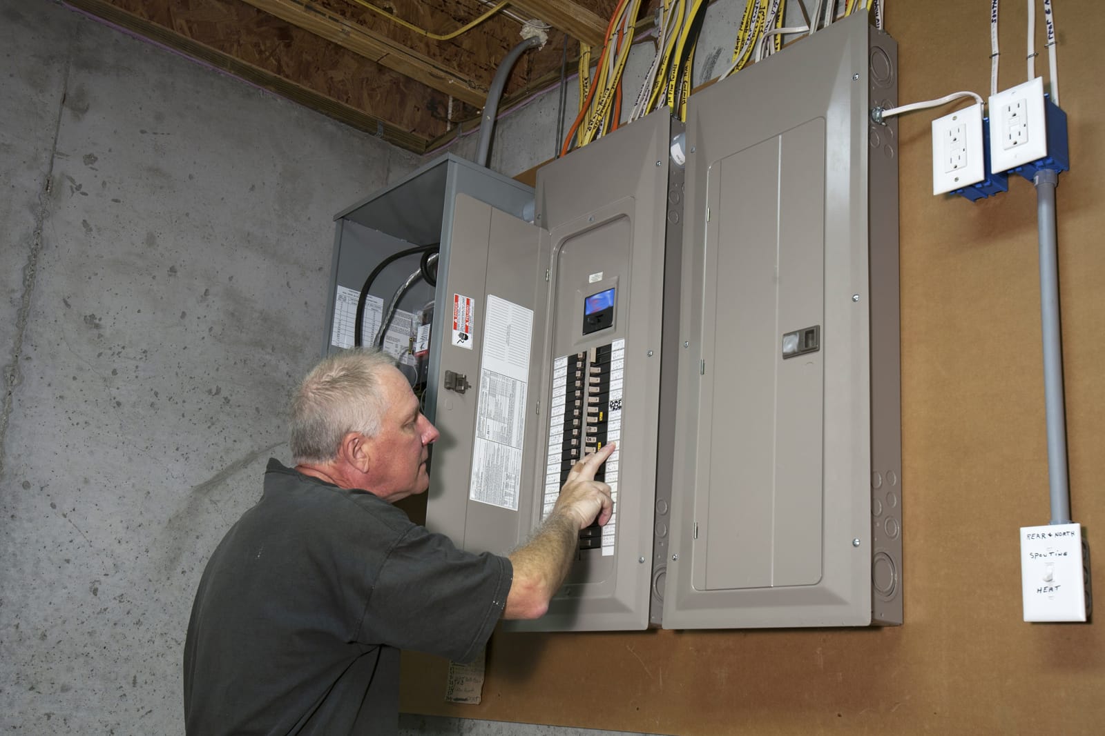 Man standing next to fuse box in a basement